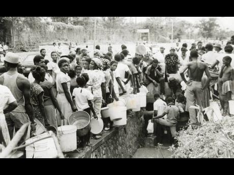 Credit: Gleaner Archives Wherever water can be found the people rush to get some. Here, a group on St John’s Road in Spanish Town, St Catherine, awaits their turn to fetch water from this broken main. Some said they had travelled from as far as Ensom City.