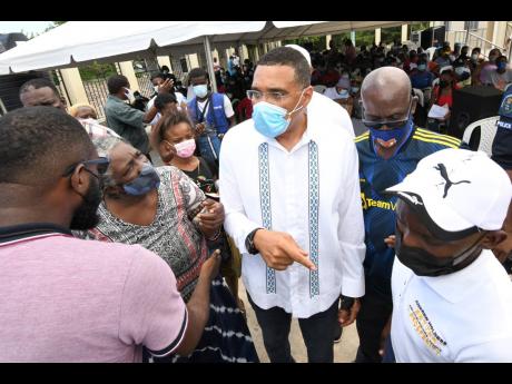 Prime Minister Andrew Holness (centre) and Desmond McKenzie (second right), minister of local government, chat with residents of Olympic Gardens.