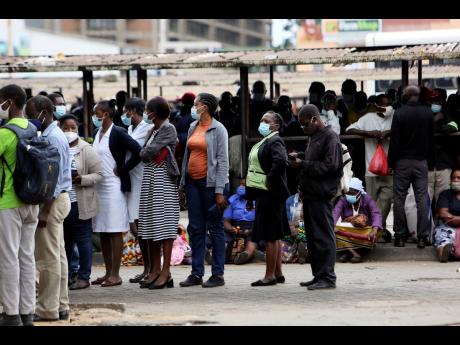People wait at a bus station in Harare, Zimbabwe, Wednesday, Sept, 16, 2021. Zimbabwe has told all government employees to get vaccinated against COVID-19 or they will not be allowed to come to work. 