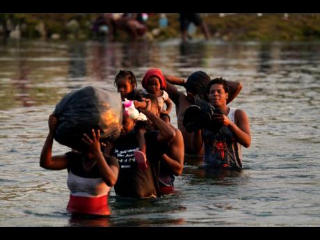 Migrants, many from Haiti, wade across the Rio Grande from Del Rio, Texas, to return to Ciudad Acuna, Mexico, on Tuesday to avoid deportation from the US. 