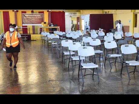 A sanitation worker walks through an almost empty auditorium at Dinthill Technical High School in St Catherine during a vaccination blitz on Sunday. Approximately 7.7 per cent of the Jamaican population has been fully vaccinated. The country is targeting f