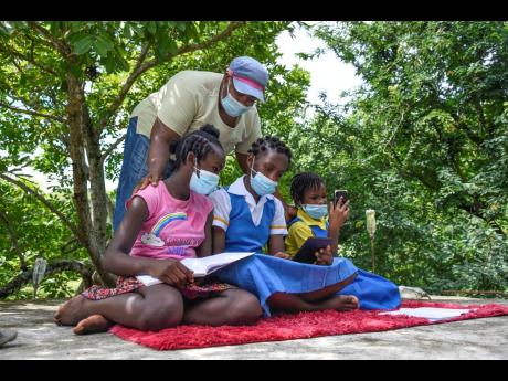 Andria McCooty checks on (from left) Lyssons Primary grade six student Brihana Stewart; Yashida McCooty, a grade eight student of Seaforth High; and Sarah Wilson, who is in grade four at Grants Pen Primary, as they sit atop her roof in River Head, St Thoma
