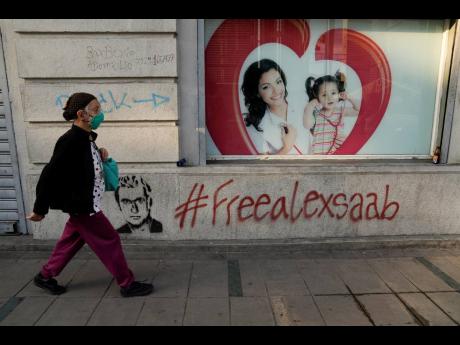 Credit: AP
A pedestrian walks past graffiti asking for the freedom of Colombian businessman and Venezuelan special envoy Alex Saab, in Caracas, Venezuela, on Saturday. Saab, a top fugitive close to Venezuela’s socialist government, was put on a plane from Cape Ver