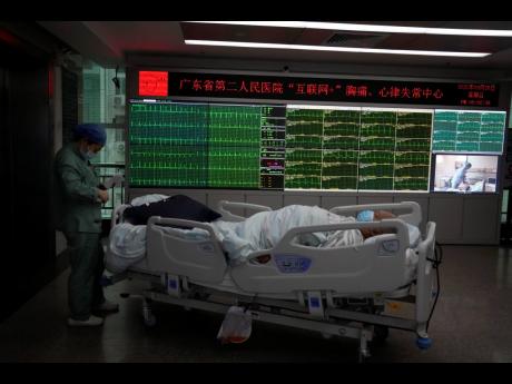 A patient moves past a display showing the real-time electrocardiograms of patients at the department of cardiovascular medicine of the Guangdong Second Provincial General Hospital in Guangzhou, in southern China’s Guangdong province, Sunday, September 2