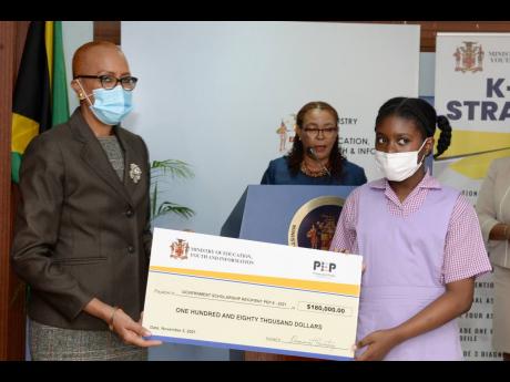 Minister of Education, Youth and Information Fayval Williams (left), presents Adrianna McDougall with a symbolic cheque for $180,000, during the virtual Primary Exit Profile (PEP) scholarship awards ceremony held on Tuesday.  Adrianna, who is a former stud