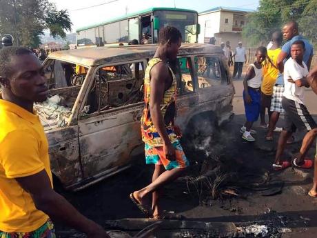 People gather at the scene of a tanker explosion after it was struck by a truck in the Wellington suburb of Sierra Leone's capital Freetown on Saturday. Authorities say at least 98 people are dead and several others critically wounded after an oil tanker e