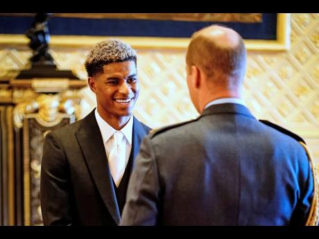 Marcus Rashford flashes a big smile during his investiture ceremony at Windsor Castle in England.