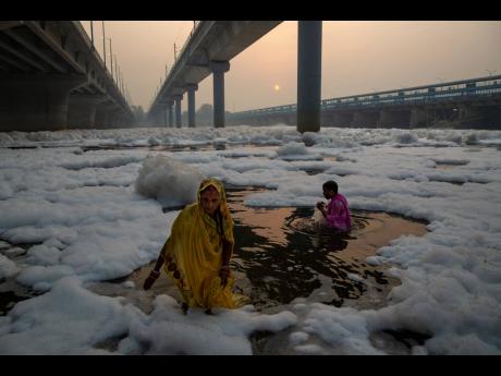 Indian Hindu devotees perform rituals in the Yamuna River, covered by chemical foam caused by industrial and domestic pollution, during the Chhath Puja festival in New Delhi, India, yesterday.