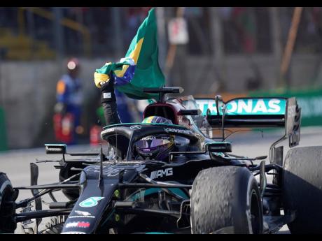 Mercedes’ Lewis Hamilton holds a Brazilian flag as he celebrates wining the Brazilian Formula One Grand Prix at the Interlagos racetrack in Sao Paulo, Brazil, yesterday.