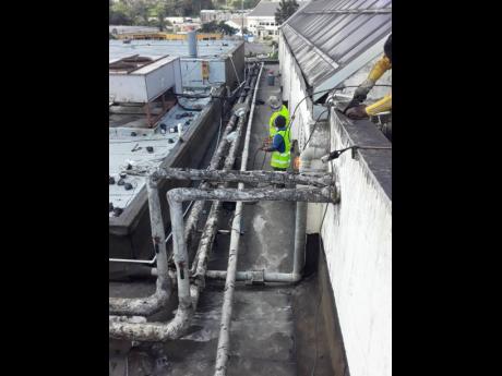 Workmen effecting repairs to a section of the roof of the Mandeville Regional Hospital in Manchester on Thursday.