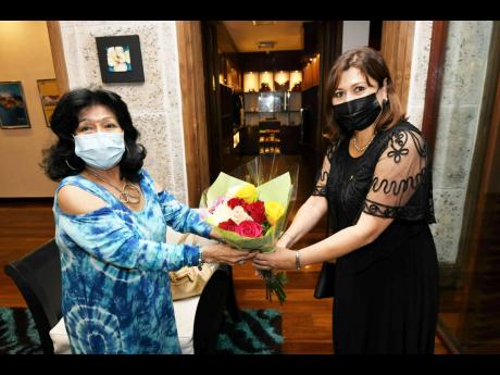 Ambassador Elza Moreira Marcelino de Castro of Brazil (right) graciously hands a bouquet to Consul of Ecuador Clelia Barreto de Hunter, who hosted the welcome reception for newly accredited female diplomats at the Spanish Court Hotel in New Kingston.