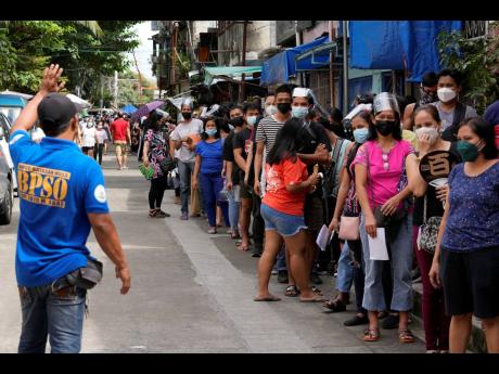 Residents wait to be inoculated with COVID-19 vaccines outside a school during the first day of a nationwide three-day vaccination drive in Quezon city, Philippines on Monday. 