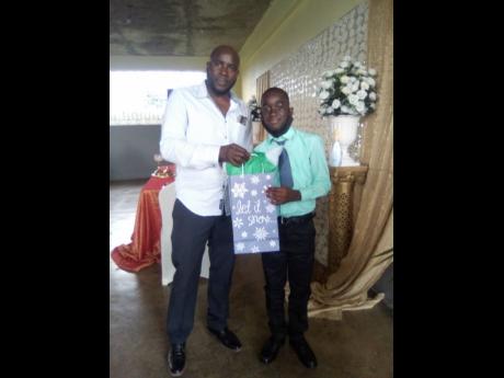 Philanthropist Hopeton Brown hands a gift package to sponsored student, Najay Simpson at the function on Friday, November 26.