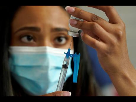 Licensed practical nurse Yokasta Castro, of Warwick, RI, draws a Moderna COVID-19 vaccine into a syringe at a mass vaccination clinic, May 19 at Gillette Stadium, in Foxborough, Massachusetts.