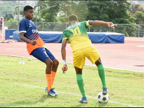 Excelsior High School’s Rojaughn Joseph (right) stands on the ball as Dunoon’s Gerrard Clunis tries to close him down. 