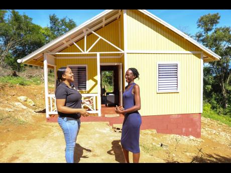 Credit: Contributed Trisha-Anne Bennett (right) expresses her gratitude to Crystal Young, marketing assistant at Wisynco, during a visit to check on Bennett and her family in Holt, St Elizabeth, on November 20. Bennett is the beneficiary of a home sponsored by Wisynco’s BOO