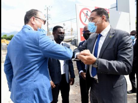 Site meeting: Prime Minister Andrew Holness (right) is greeted by William Tavares-Finson, director of Audere Holdings, during the groundbreaking of One Belmont, a commercial building under construction along Belmont Road in New Kingston. Ike Johnson (secon