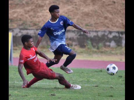 Jamaica College’s Shemron Phillips (right) evades a sliding tackle from Bridgeport High School’s Devaun Webb during their ISSA/Digicel Manning Cup match at Stadium East in Kingston on Saturday.