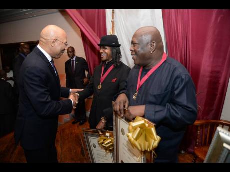 Governor General Sir Patrick Allen (left), congratulates ‘Robbie’ Shakespeare (right), and ‘Sly’ Dunbar of Sly and Robbie after they were awarded the Gold Musgrave Medal in 2015 by the Institute of Jamaica.