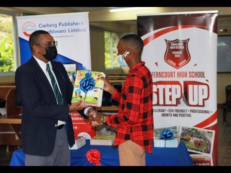 Nicklaus Bromfield, Carlong Publishers (Caribbean) Ltd Western Region marketing representative, presents $60,000 worth of resource material to Kevin Peart, the young man who has converted an old bar into a classroom where he is assisting children in his co