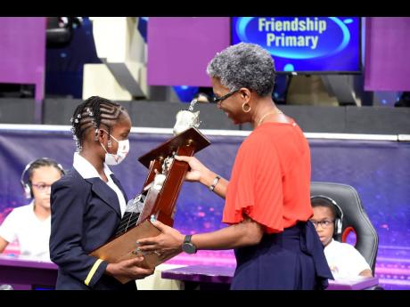 Television Jamaica General Manager Claire Grant presents the championship trophy to Monneesa Daley, captain of the Friendship Primary’s team, after the Spanish Town-based school won this year’s TVJ’s Junior Schools’ Challenge Quiz Competition last 