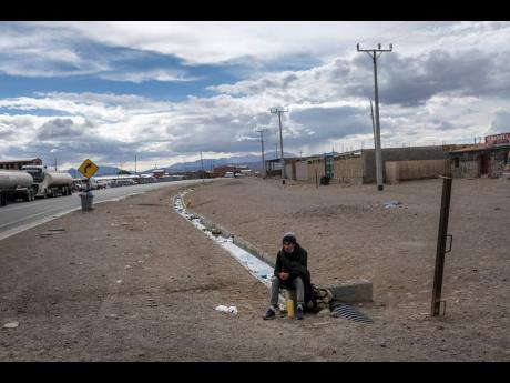 Venezuelan migrant Richard Rojas rests on a road after crossing into Chile from Bolivia, in Colchane, Chile, Thursday, December 9, 2021. Latin America is facing a decade of lost economic growth.