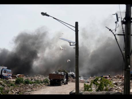 A truck drives through thick smoke at the Riverton disposal site in St Andrew.