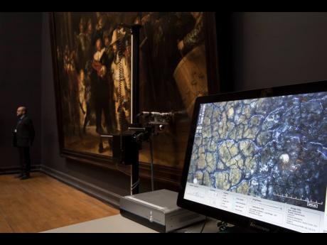 Credit: AP/ File In this 2018 photo a microscopic image enlarging a 4x6 millimetre part of the painting on Rembrandt’s Night Watch, which will be restored in the public eye, is seen on a screen next to the painting at the Rijksmuseum in Amsterdam, Netherlands. Rembrandt