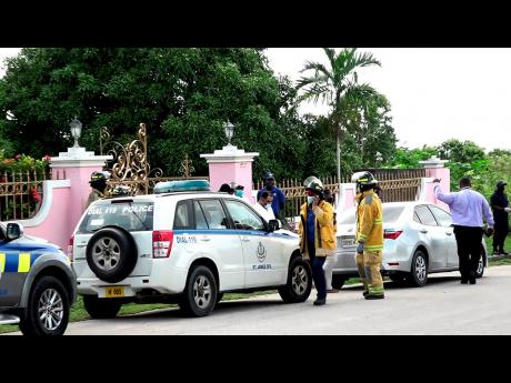 Police and firefighters gather outside the Ironshore home of Pastor Kevin O. Smith (centre) as they conducted a search of properties owned by him.