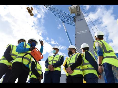 Credit: Ian Allen/Photographer Kingston Wharves Ltd’s (KWL) Kavelle Campbell (second left) demonstrates how to operate the new crane remotely while Prime Minister Andrew Holness (centre) and Professor Gordon Shirley (left, partly hidden), president and CEO of the Port Authority of Jam