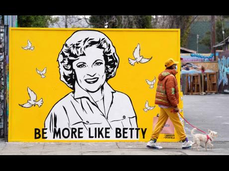 A man walks a dog past a new mural of the late actress Betty White by artist Corie Mattie, on Tuesday in Los Angeles. Mattie added a QR code to the mural so people walking by can donate to the local shelter Wagmor Pets Dog Rescue in honour of White, an ani