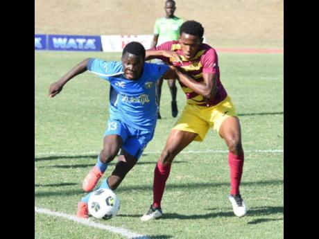 Clarendon College goalscorer, Keheim Dixon (left), dribbles by his Dinthill Technical opponent, Shamar Martin, during their Champions Cup final game at the Stadium East field earlier today. Clarendon won the game 1-0.