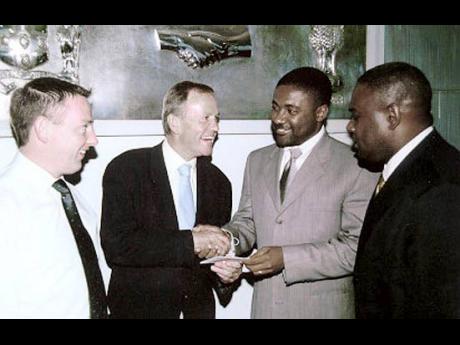 Digicel investor Leslie Buckley (second left) hands over the company’s commitment letter to then telecoms minister, Phillip Paulwell, while Seamus Lynch (left) and then Parliamentary Secretary Colin Campbell look on.