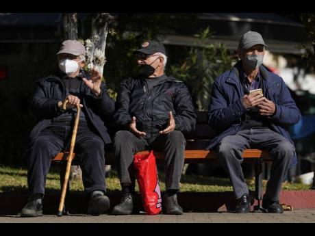 Three elderly men wearing FFP2 face masks to curb the spread of coronavirus, sit on a bench in Athens, Greece yesterday. 