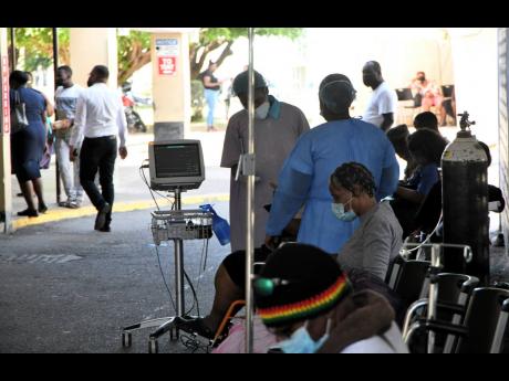 Healthcare workers attend to patients hooked up to oxgen tanks in a driveway at the University Hospital of the West Indies on Monday.
