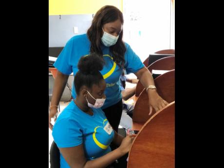 Credit: Asha Wilks Computer studies teacher Jone Knight instructs Shanjay Hall during a skills training programme, funded by the USAID, in Jones Town recently.