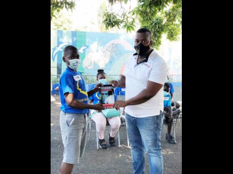 Credit: Asha Wilks Pastor Jayson Downer presents Jakeem Warson with a keepsake from a motivational rap session at the Jones Town community development and skills training programme funded by the USAID.