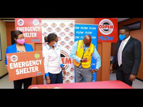 Richard Thompson (second right), acting director general, ODPEM, tests the strength of one of the 1,000 shelter manager vests donated by Flow Jamaica. Stephen Price (right), Flow’s VP and general manager, and Heather Wallen-Bryan (second left), Flow’s 
