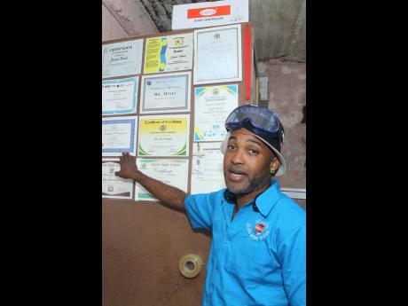 Credit: Nathaniel Stewart Jason Hines of Glasswork Design, Spalding, Clarendon, displays some of the many certificates received from schools whose students he would have impacted.