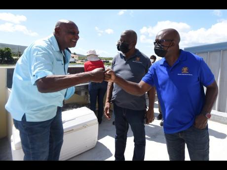 Ministry of Agriculture and Fisheries Pearnel Charles Jr. (right) and Frank Witter, minister of state in the Ministry of Agriculture and Fisheries, are greeted by Noel Wilson, owner of Aqua Fish Farms in Hill Run, St Catherine on Wednesday, during a tour o