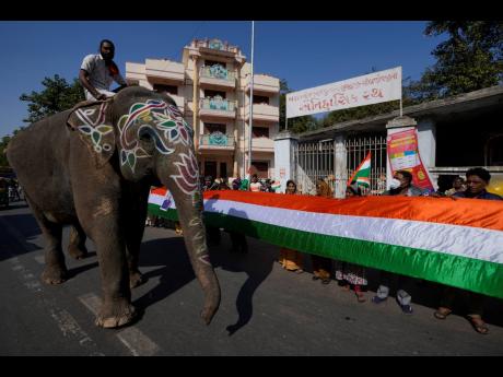
A mahout sits on an elephant as people display a huge national flag during India’s Republic Day celebrations in Ahmedabad, India