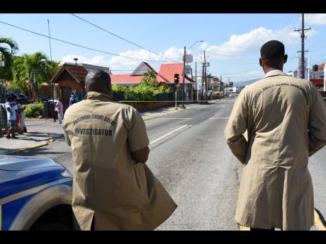 Crime-scene Investigators make their way towards the site of a shooting along Old Hope Road.