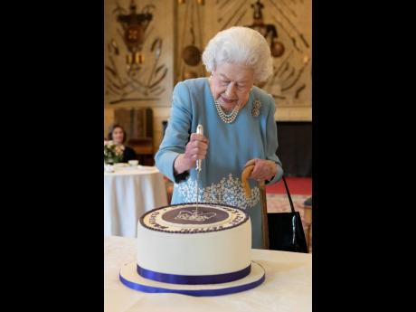 Britain’s Queen Elizabeth II cuts a cake to celebrate the start of the Platinum Jubilee, at Sandringham House, her Norfolk residence, in Sandringham, England on Saturday.