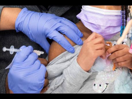 A 5-year-old girl receives her first dose of the Pfizer COVID-19 vaccine from a nurse in the cafeteria of the Pittsburgh Langley K-8 school.