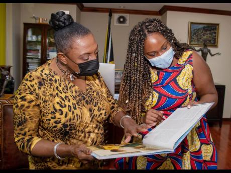 Kuba Shand-Baptiste (right) and Minister Olivia ‘Babsy’ Grange looking through ‘Women of Distinction’.