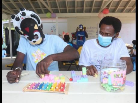 A child from the West Haven Children’s Home (left) is assisted by Clayton Parchment, member of the Stardae Charity Group, during a treat on Monday.