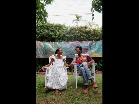 Guyana-born artist Kwesi Abbensetts and his partner, Anya Peters, relaxing in front of one of his artwork at his recent solo exhibition in St Andrew.