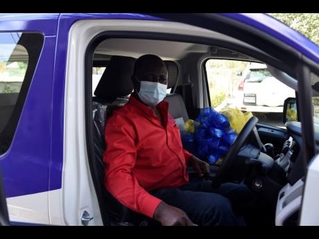 Driver Ronald Morgan is happy for the new 2021 Toyota Hiace bus that was donated to the Jamaica Cancer Society on Monday by the Rotary Club of St Andrew North.