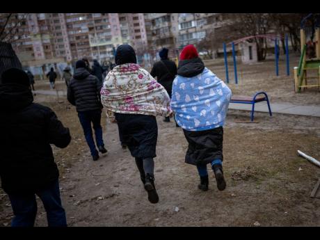 
People run to take shelter while the sirens sound announcing new attacks in the city of Kyiv, Ukraine, Friday, Feb. 25, 2022. (AP Photo/Emilio Morenatti)