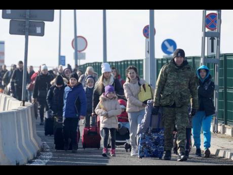 
A Polish border guard assists refugees from Ukraine as they arrive to Poland at the Korczowa border crossing, Poland on Saturday.